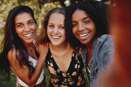Group of happy diverse multiracial girl friends taking a selfie outdoors in the park on a sunny day smiling -の写真素材