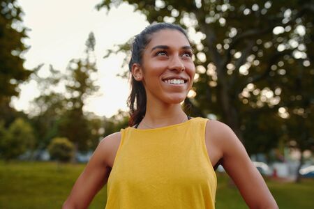 Portrait of a smiling happy fit slim young woman looking motivated and determined in the parkの写真素材