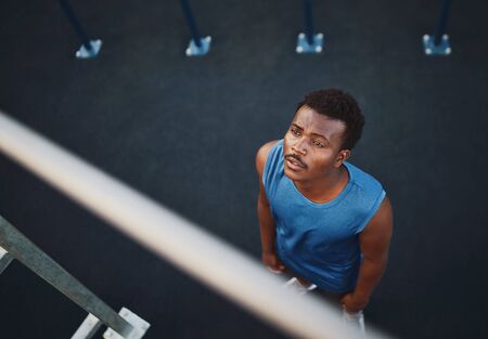 An overhead view of a young african american male athlete prepares to do pull ups on horizontal bar - man afraid of exerciseの写真素材