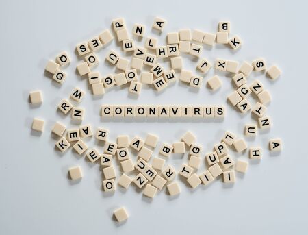 Coronavirus covid19 spelt on  tiles and surrounded by other tilesの写真素材