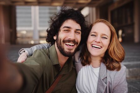 Cheerful young professional couple taking a selfie using smartphoneの写真素材