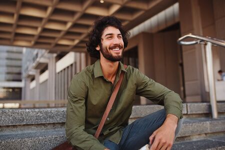 Handsome young man sitting on stairs while looking awayの写真素材