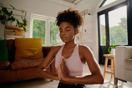 Portrait of young african woman with closed eyes practicing yoga with joint handsの写真素材