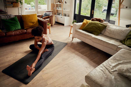 High angle view of young happy woman at home doing stretching exercise