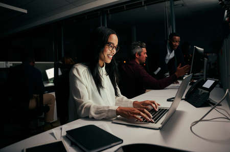 Female employee busy in her work on laptop in office and with colleagues at backgroundの写真素材