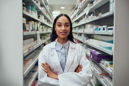 Portrait of young female pharmacist wearing labcoat standing in chemistの写真素材