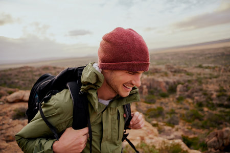 Happy male hiker wearing backpack climbing mountain trail in sportswear