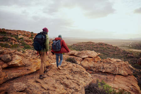 Rear view of young male hiking friends climbing mountain hillの写真素材