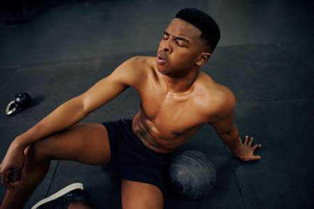 African American male resting on the gym floor after an intense cross fit session. Mixed race...