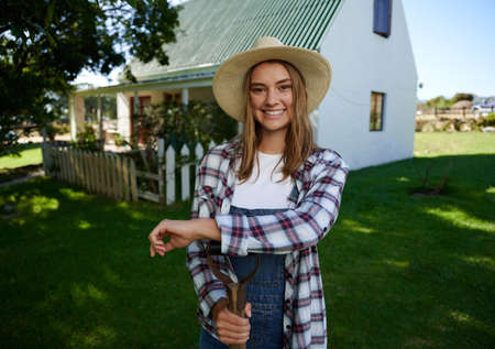 Caucasian smiling female farmer standing outdoors leaning on pitch fork. High quality photoの写真素材