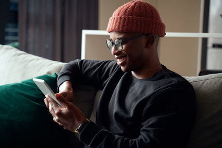 Happy adult black male using a tablet. Modern apartment on the sofa.の写真素材