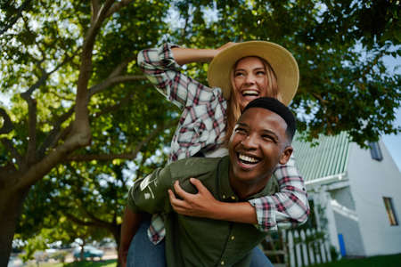 Caucasian female farmer bonding with male friend enjoying piggy back ride. High quality photoの写真素材