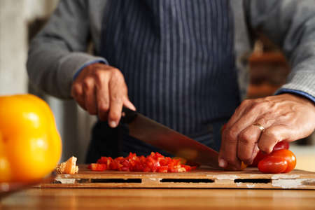 Close up of hands, elderly multi-cultural male chopping up vegetables for breakfast. Retired at home.の写真素材