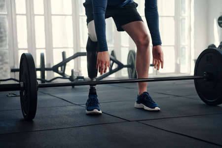 Photo of male Paralympic athlete with prosthetic leg about to lift a barbellの写真素材