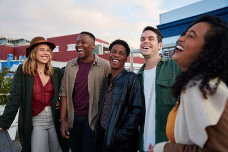 Stylish, diverse group of friends standing together rooftop at party in city. City living in...
