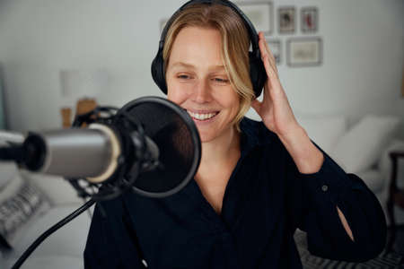 Caucasian female business woman working from home speaking into microphone recording podcast. High quality photoの写真素材