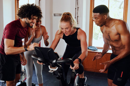 Determined multiracial young adults in sportswear motivating friend on exercise bike at the gymの写真素材
