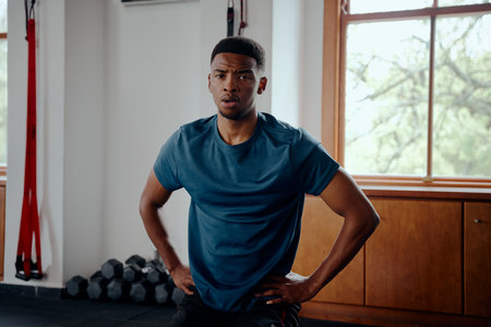 Young black man in sportswear taking a break between exercises at the gymの写真素材