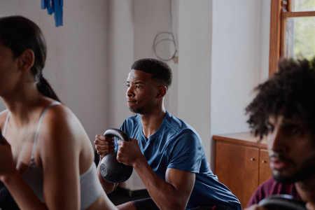 Three multiracial young adults in sportswear doing kettlebell squats at the gymの写真素材