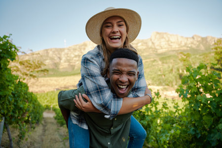 Young multiracial couple wearing casual clothing smiling while giving piggyback on farmの写真素材