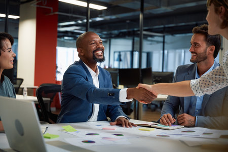 Four multiracial business people wearing businesswear smiling and shaking hands during meeting in...