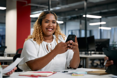 Three multiracial business people wearing businesswear using technology during meeting in officeの写真素材