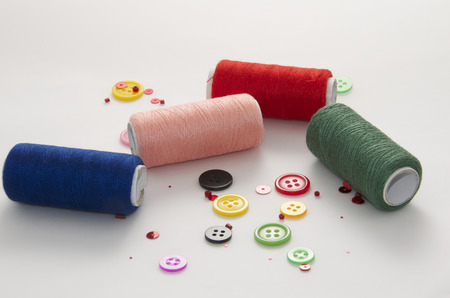 Textile ,Coils of Colored Threads and Buttons on White Background