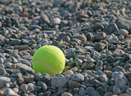 Close up of tennis ball on beach with pebblesの写真素材