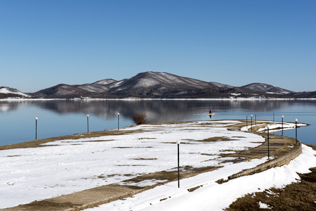 Tranquil scenery.Landscape,Black snowy mountain,clear sky and a water bike on lake at a winter day,Greeceの写真素材