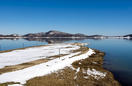 Tranquil scenery.Landscape,Black snowy mountain,clear sky and a water bike on lake at a winter day,Greeceの写真素材