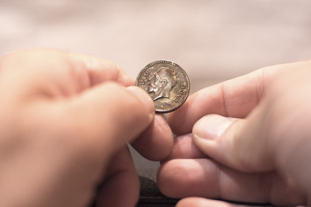 Close up capture of an Caucasian man hands holding and old greek new years cake coin showing king faceの写真素材