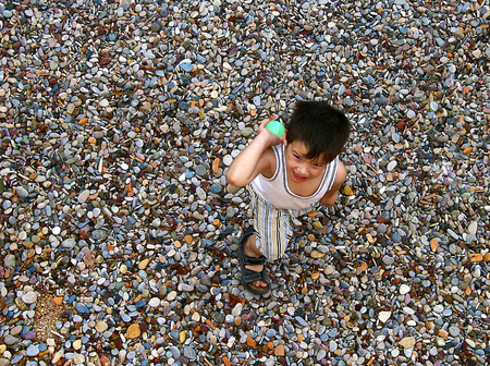 Happy boy plaing with a green ball at the beachの写真素材