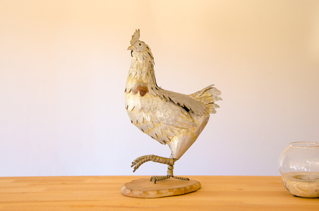 Decorative metalic rooster on wooden tableの写真素材