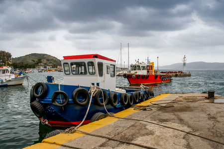 A rainy wintry day under a heavy sky. Fishing boats at the small harbor. Pachi,Greece