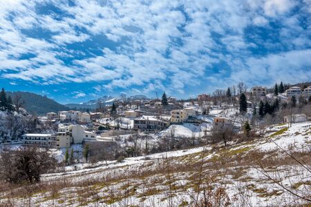 Mountainous snowy village under cloudscape on Plastira lake in central Greeceの写真素材
