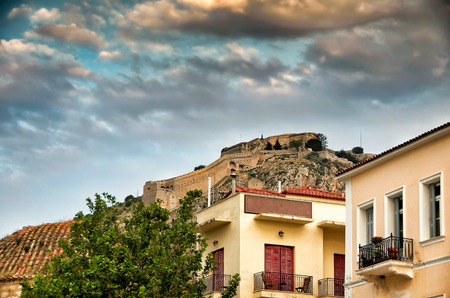 Palamidi fortress up on the hill and hosues on Nafplion city under a dramatic skyの写真素材