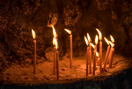 Lighting candles on rocks inside a cave orthodox chapel .Greeceの写真素材