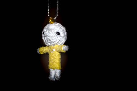 Cute little doll isolated on black background. Charm keychain for a children bag. Kids sewing crafts...