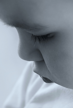 Conceptual Monochrome old style photo of little boy who looking down. Close up portraitの写真素材