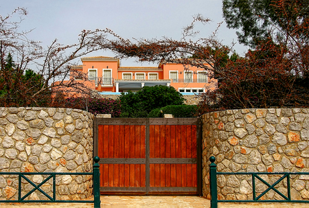 House with a beautiful wooden gate surrounded by stone walls.の写真素材