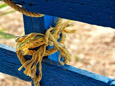 Thick jute yellow rope  hanging from blue painted wooden planksの写真素材