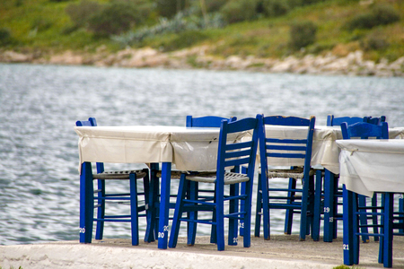 Tables and blue chairs by the seaside. Greece.の写真素材