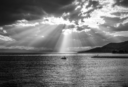 Fishermen after a storm under a dramatic sky with sunbeamsの写真素材