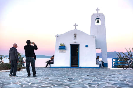 Rafina,Greece -03/25/2017: People photo shooting, resting and enjoy the view. White small orthodox chapel dedicated to St Nikolaos.のeditorial素材