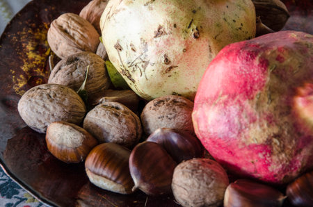 Pomegranates chestnuts, and nuts, autumn fruits composition on a plateの写真素材