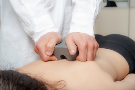 Manual, physio and kinesio therapy techniques performed by a male physiotherapist on a training plastic spine and a female patientの写真素材