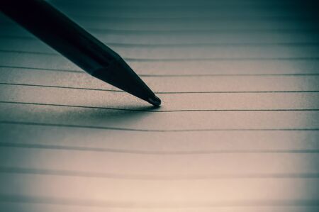 A sheet of paper in a line with a black pencil close up
