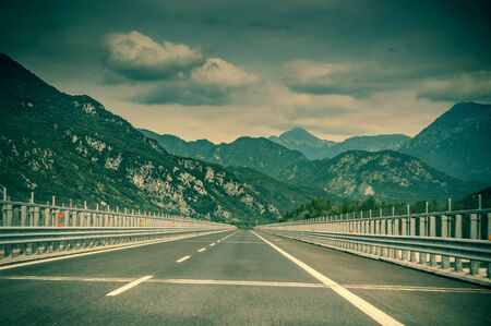 The road goes to the horizon against the backdrop of the mountains in details