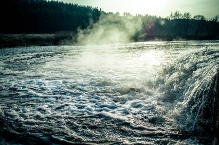 A stream of water pours into the river close up