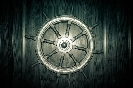 Old ship steering wheel on a wooden wall in detailの写真素材